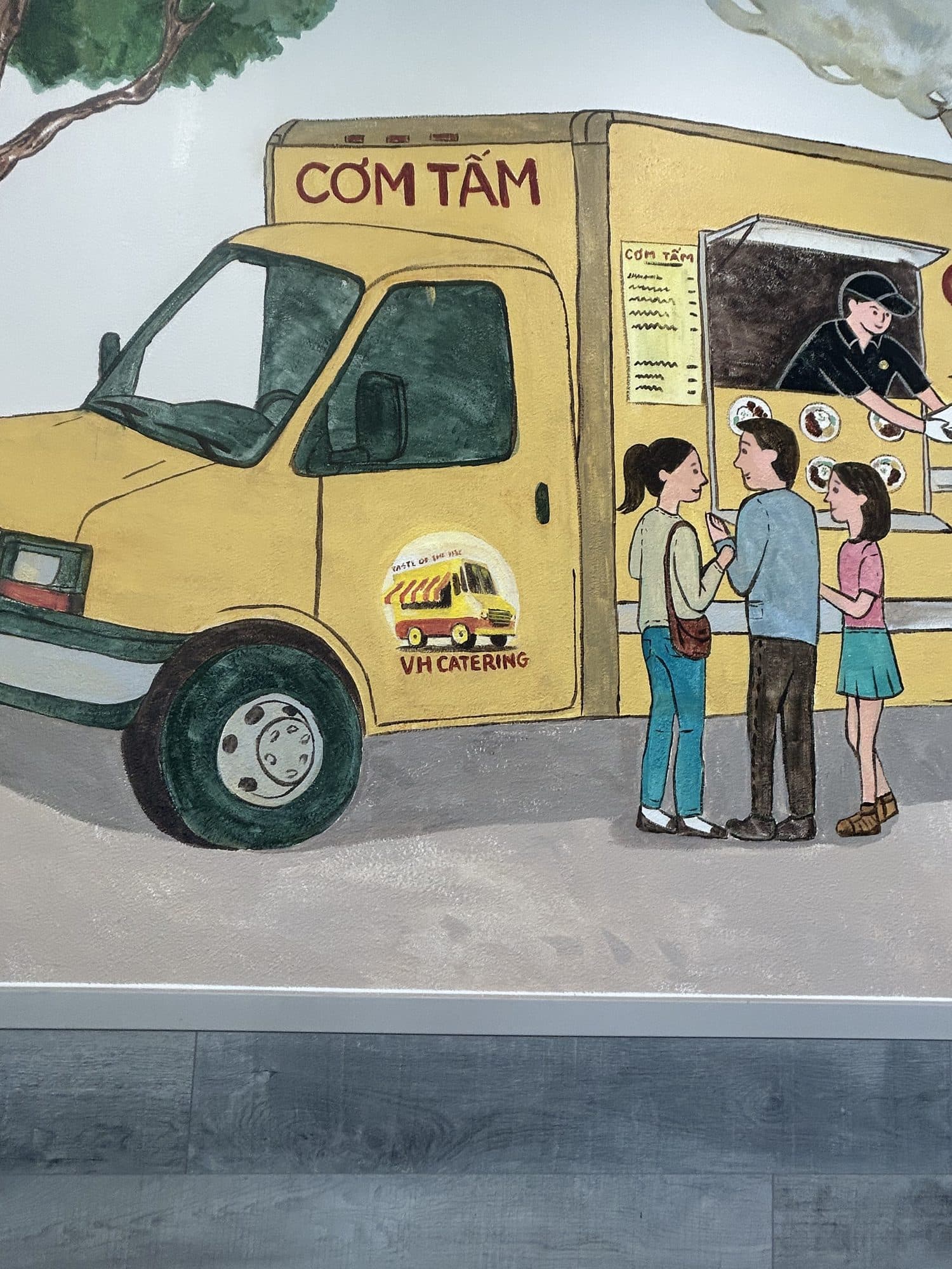 Detail of the painted food truck with the Cơm Tấm sign and a family waiting