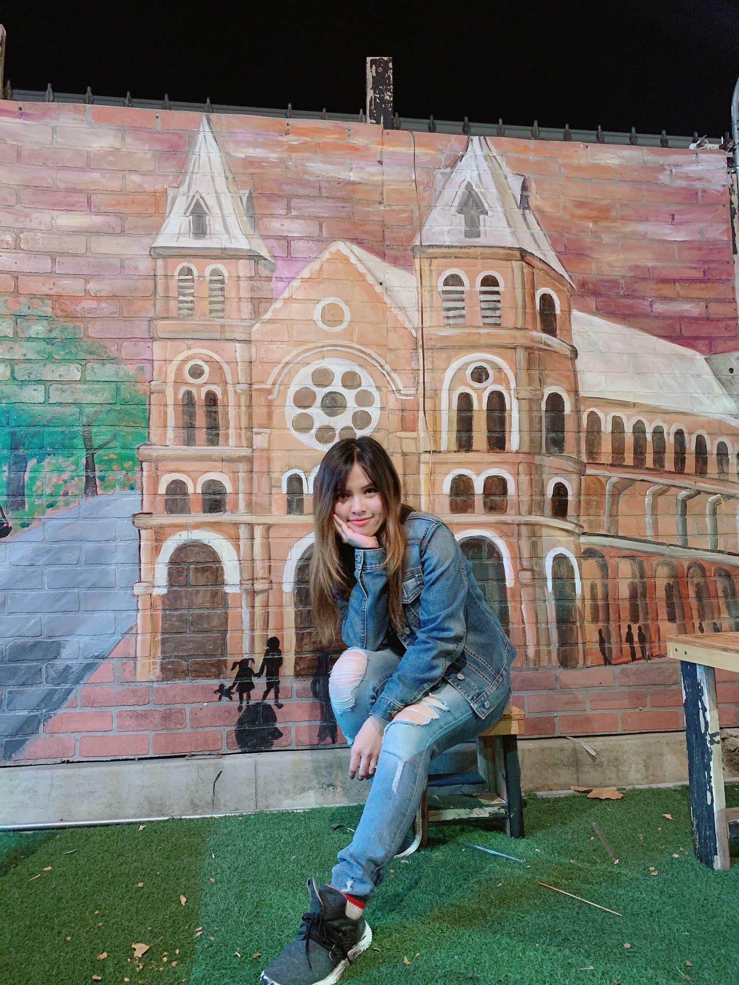 Woman posing in front of a painted mural of Saigon's Notre-Dame Cathedral